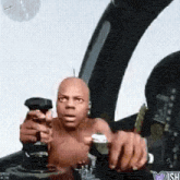 a man without a shirt is sitting in the cockpit of a plane holding a remote control .