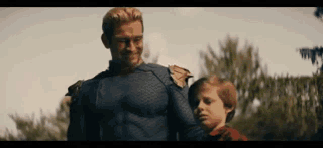 a man in a superhero costume is standing next to a young boy in a field .