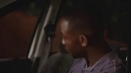 a man is sitting in the driver 's seat of a car and looking out the window .
