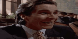 a man in a suit and tie is smiling while sitting at a table in a restaurant .
