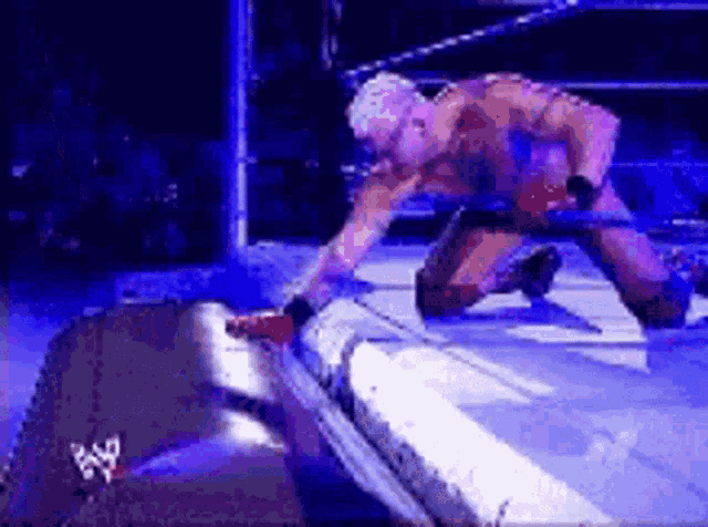 a wrestler is kneeling down in a wrestling ring while holding a sword .