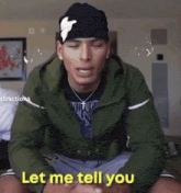 a man wearing a green jacket and a black hat is sitting down and says let me tell you