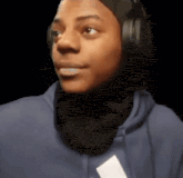 a young man wearing headphones and a scarf around his neck is making a funny face .