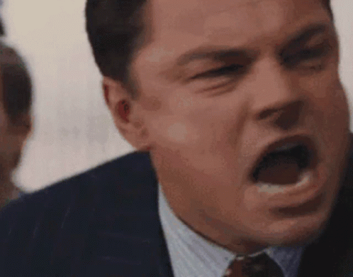a man in a suit and tie is screaming with his mouth open .