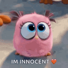 a pink angry bird from the angry birds movie is sitting on the ground with a heart . a pink angry bird from the angry birds movie is sitting on the ground with a heart .