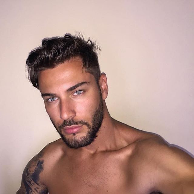 This may contain: a close up of a shirtless man with tattoos on his arms and chest, looking at the camera
