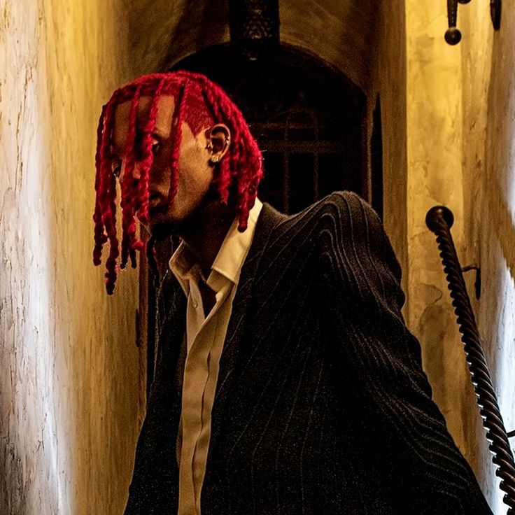 This may contain: a man with red dreadlocks walking down a hallway