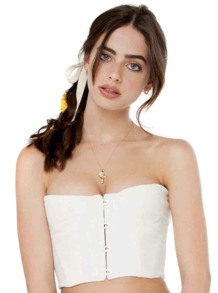 This may contain: a woman wearing a white crop top with a flower in her hair and a chain around her neck