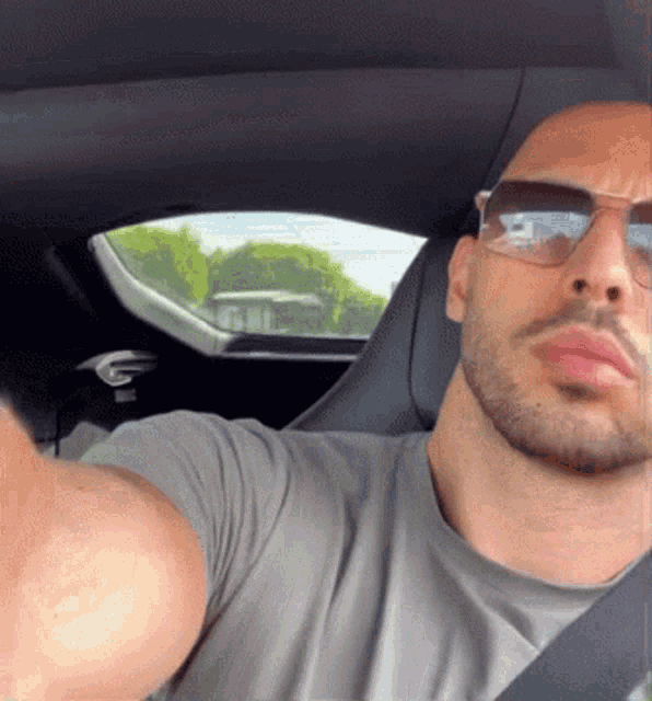 a man wearing sunglasses is taking a picture of himself in a car