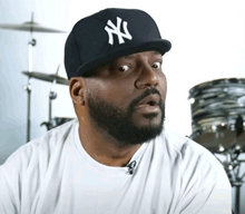 a man with a beard wears a black ny hat