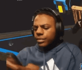 a man wearing headphones and a blue hoodie is looking at his cell phone .