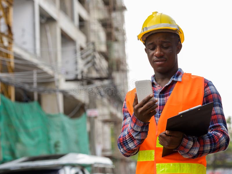 young-black-african-man-construction-worker-holding-clipboard-using-mobile-phone-building-site-young-black-african-man-130657196.jpg