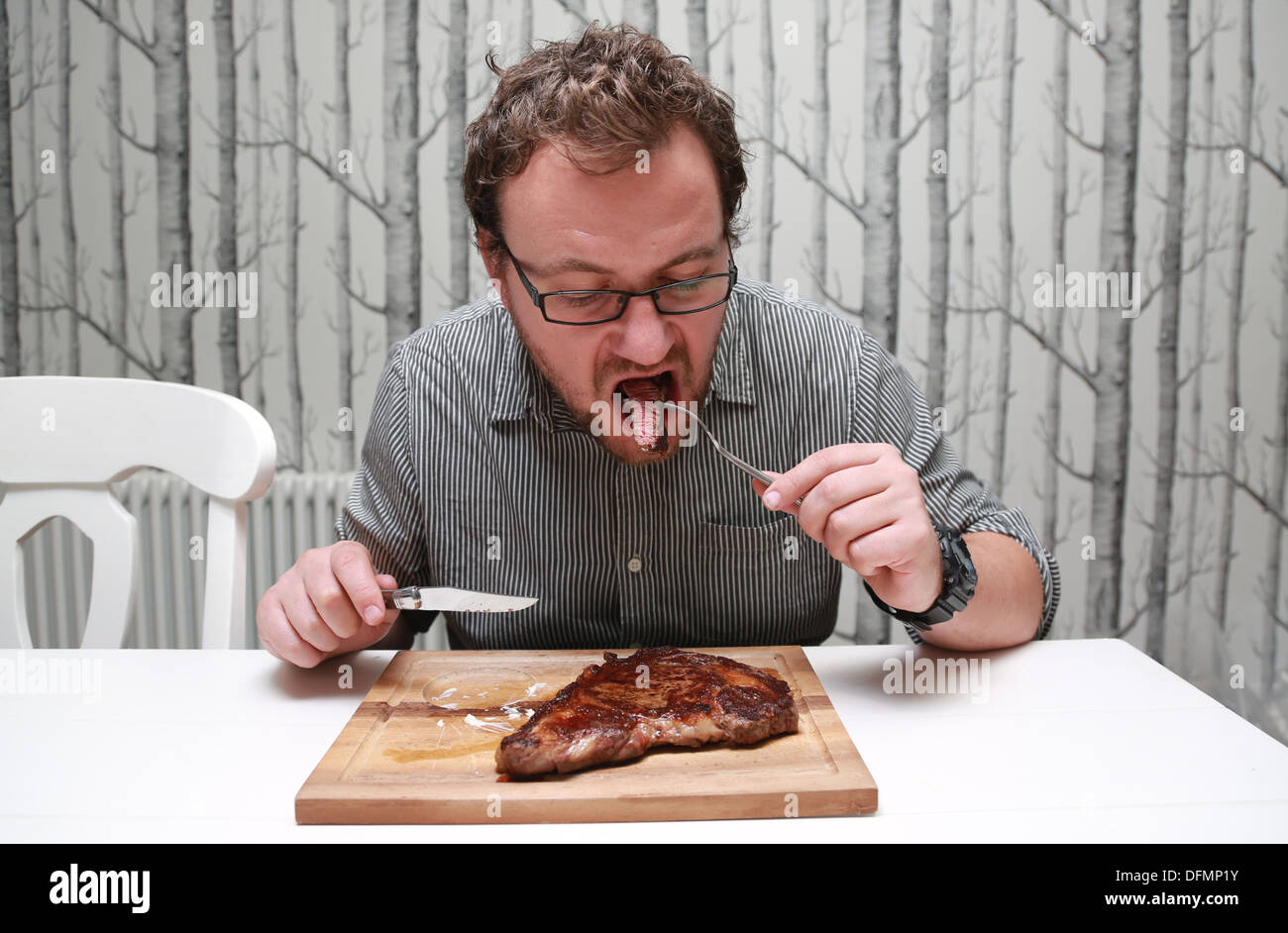 man-eating-a-large-juicy-steak-with-chips-DFMP1Y.jpg