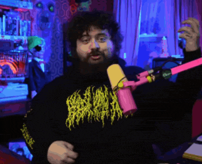 a man with a beard is standing in front of a pink and yellow microphone .
