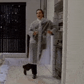 a man in a clear plastic raincoat is standing in a room .