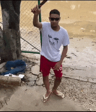a man wearing a white shirt that says ' yoki ' on it is holding a baseball bat