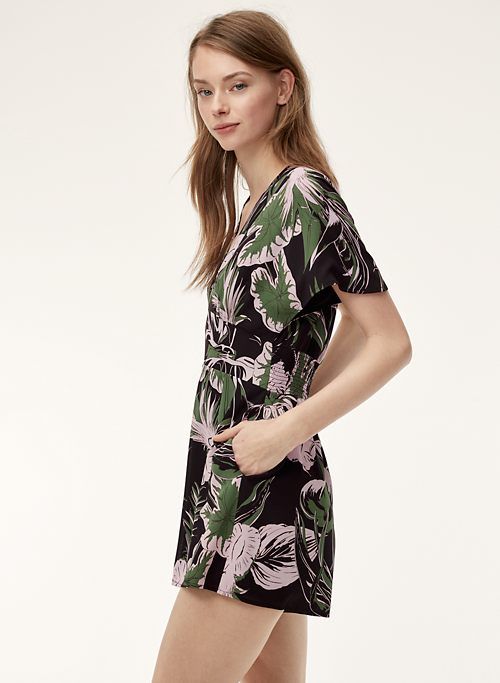 This may contain: a woman is standing in front of a white background wearing a black and green dress