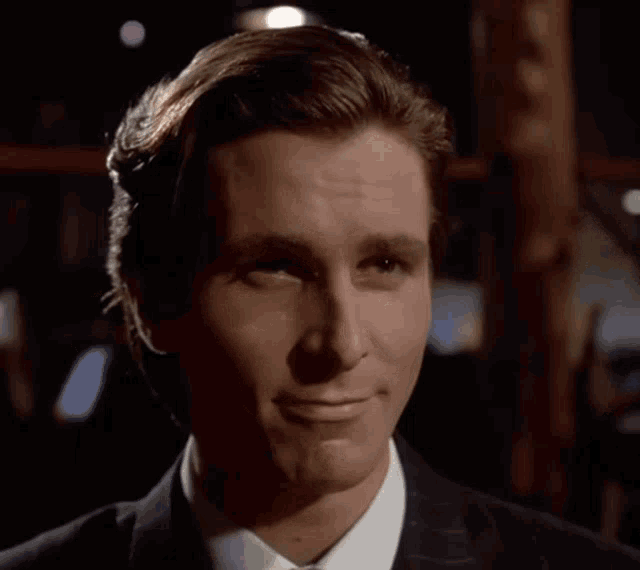 a man in a suit and tie is smiling with his eyes closed