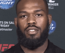 a man with a beard is standing in front of a bud light sign