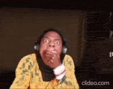 a woman wearing headphones is making a funny face while covering her mouth .
