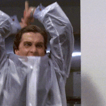 a man in a blue shirt is covering his face with plastic