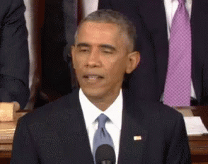 barack obama is making a funny face while speaking into a microphone .