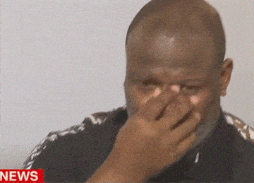 a man is covering his nose in front of a news screen