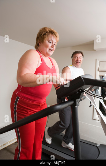 overweight-couple-using-exercise-machines-akjtk9.jpg