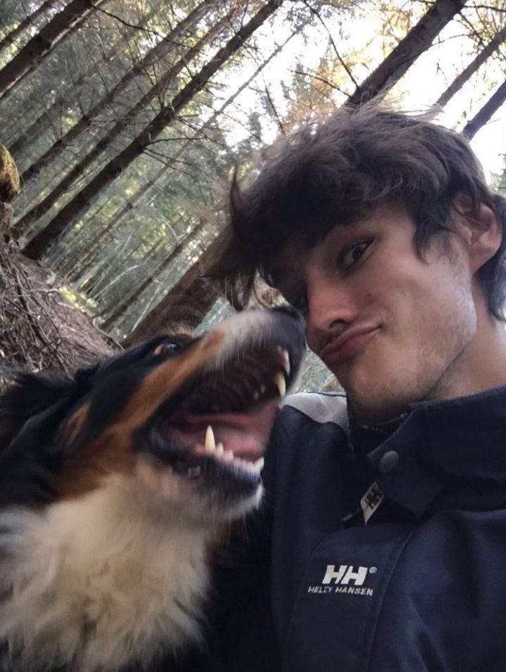 This may contain: a man and his dog pose for a photo in front of some trees with their mouths open