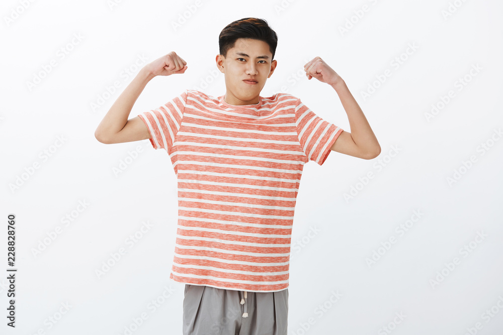 Look how strong I am. Portrait of self-assured funny young slim asian guy  raising hands to show biceps or muscles, starting working out, straining  and holding breath to look masculine Stock Photo |