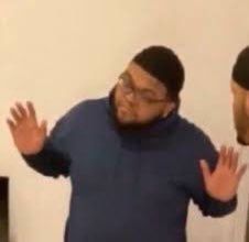 This may contain: two men standing next to each other with their hands in the air and one man wearing glasses