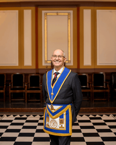 a man in a masonic costume stands in a room with a checkered floor