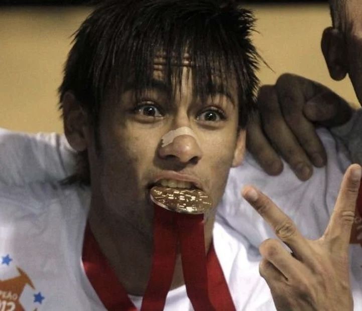 This may contain: two men with medals around their necks making the peace sign and pointing fingers at them