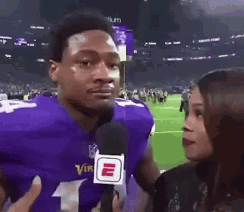 a football player is being interviewed by a woman on a field .