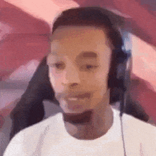 a man wearing headphones and a white shirt is sitting in front of a computer screen .