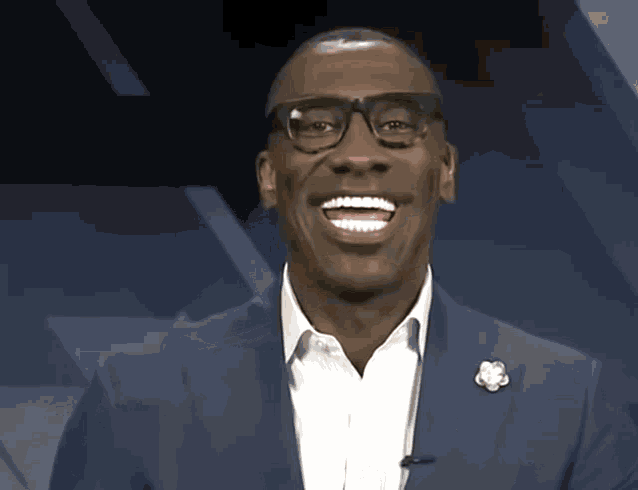 a man wearing glasses and a blue suit smiles