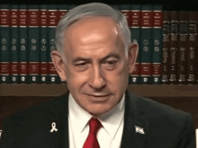 a man in a suit and tie with a red ribbon on his shirt