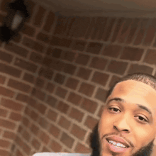 a man with a beard is taking a selfie with a brick wall in the background