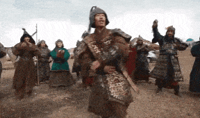 a group of men in armor are standing in a field with their arms in the air