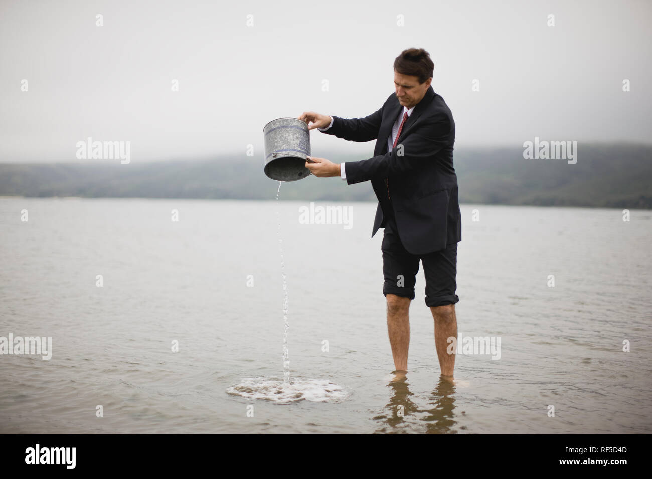 businessman-pouring-water-out-of-bucket-RF5D4D.jpg