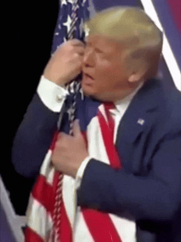 a man in a suit and tie is holding an american flag in his hands