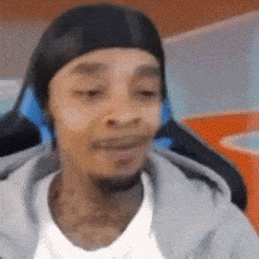 a man wearing a headband and headphones is sitting in a chair and making a funny face .