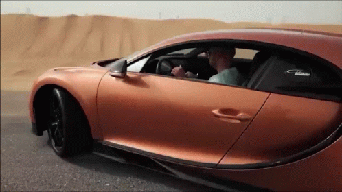 a man is driving a bugatti chiron car on a desert road