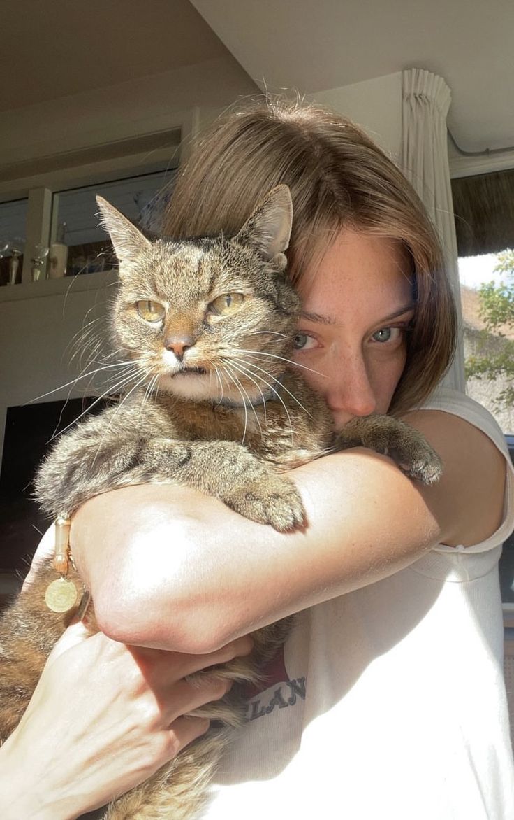 This may contain: a woman holding a cat in her arms