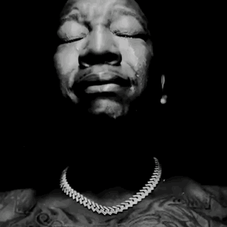 a black and white photo of a man with his hands folded in prayer .