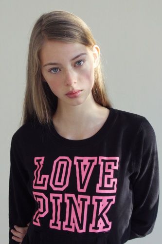 This may contain: a young woman wearing a black sweater with pink letters on it and the words love pink written across the chest