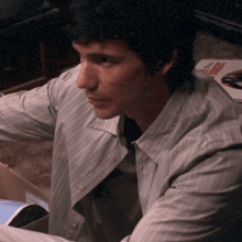 a man in a striped shirt is sitting in front of a book that says ' robert '