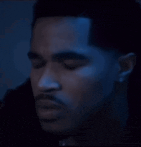 a close up of a man 's face with blue light behind him