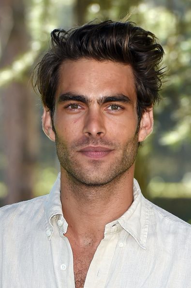 This may contain: a man in a white shirt is posing for a photo with trees in the background