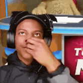 a man wearing headphones and a hat is covering his nose .